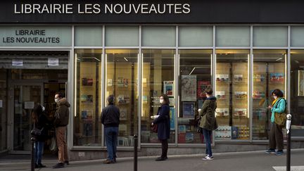 Des personnes font la queue devant une&nbsp;librairie, à Paris, le 11 novembre 2020. (VIRGINIE HAFFNER / HANS LUCAS / AFP)