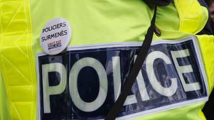 Un policier arborait un badge du syndicat Unité SGP Police-FO dénonçant le surmenage de la police. C'était en 2017 où déjà, les forces de l'ordre réclamaient de meilleures conditions de travail. (FRANCOIS GUILLOT / AFP)