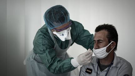 Un officier de police&nbsp;effectue un test PCR au coronavirus à l'aide d'un écouvillon&nbsp;inséré dans son nez à l'aéroport international de Bordeaux-Mérignac (Gironde) le 23 juillet 2020. (PHILIPPE LOPEZ / AFP)