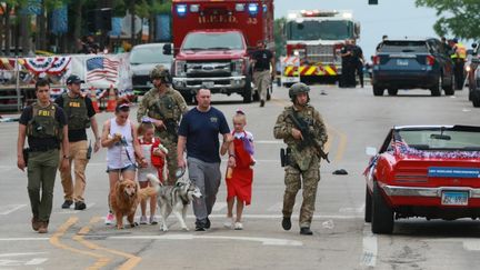 Une famille escortée par les forces de l'ordre après une fusillade à Highland Park, dans l'Illinois (Etats-Unis), le 4 juillet 2022. (MARK BORENSTEIN / GETTY IMAGES NORTH AMERICA / AFP)