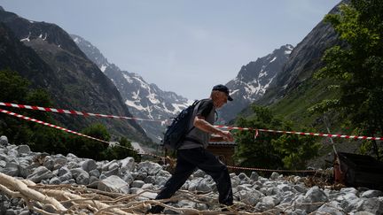 Un habitant marche au milieu des débris pour récupérer des effets personnels dans les décombres de sa maison après la crue dévastatrice du Vénéon, dans le hameau de La Bérarde (Isère), le 28 juin 2024. (ARNAUD FINISTRE / AFP)