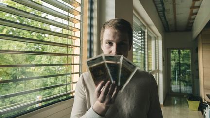 Pierre Louis, aka Price&nbsp;Pokemon, collectionne des cartes&nbsp;Pokémon&nbsp;depuis 5 ans, dans ses mains un Dracaufeu première édition. (MATTHIEU BONHOURE / RADIO FRANCE)