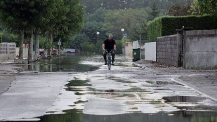 Un homme circule en v&eacute;lo dans les rues du Cailar (Gard), touch&eacute; par de fortes pr&eacute;cipitations, le 10 septembre 2005. (DOMINIQUE FAGET / AFP)