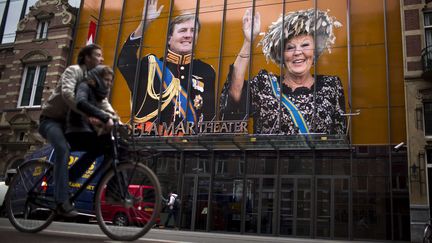 Des cyclistes passent devant un portrait de la reine Beatrix et de son fils, Willem-Alexander, expos&eacute; sur la devanture d'un th&eacute;&acirc;tre, le 30 avril 2013.&nbsp; (EMILIO MORENATTI / SIPA / AP)