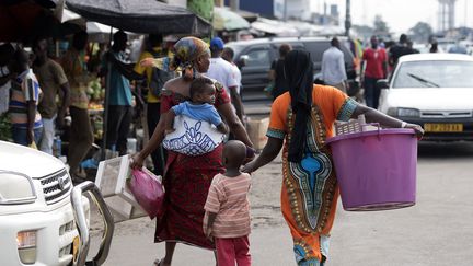 Des femmes et des enfants passent devant les étals du marché de Port-Gentil, au Gabon, le 18 janvier 2017.&nbsp; (JUSTIN TALLIS / AFP)