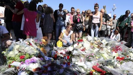 Des habitants se recueillent dans une rue de Nice, au lendemain de l'attaque au camion menée sur la promenade des Anglais, vendredi 15 juillet 2016. (VALERY HACHE / AFP)