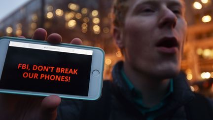 Un homme manifeste en soutien à Apple, à Washington, le 23 février 2016, en affichant sur son téléphone un message adressé aux autorités : "FBI, ne déchiffre pas nos téléphones." (PAUL J. RICHARDS / AFP)