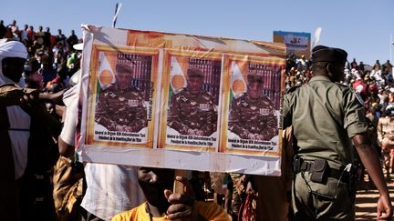 A man carries a sign of Nigerien general Abdourahamane Tiani during the festival of "National saber", major traditional wrestling championship, December 31, 2023 in Agadez.  (CAMILLE LAFFONT / AFP)