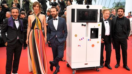 Une première à Cannes ! La montée des marches du film Sibyl a accueilli un invité surprise : le réfrigérateur star du film Yves de Benoît Forgeard. Il est entouré par l'équipe du film. (LOIC VENANCE / AFP)