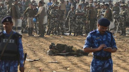 Un policier fait une sieste dans un champs pendant que ses coll&egrave;gues surveillent l'ashram du gourou&nbsp;Rampal Maharaj &agrave; Hisar (Inde), le 19 novembre 2014. (SAJJAD HUSSAIN / AFP)