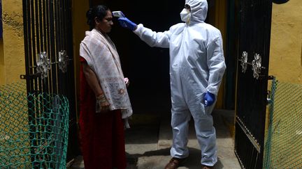 Un médecin vérifie la température d'une patiente dans le cadre d'un contrôle lié au Covid-19, le 29 juin 2020 à Chennai (Inde). (ARUN SANKAR / AFP)