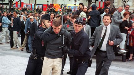 Maxime Brunerie interpellé par des policiers au milieu des Champs-Elysées, après&nbsp;qu'il a tenté d'assassiner Jacques Chirac, le&nbsp;14 juillet 2002,&nbsp;à Paris. (AFP)