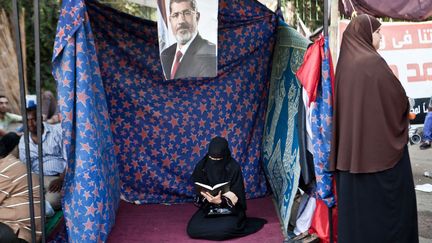 Une femme lit le Coran lors d'un sit-in pro-Morsi à l'Université du Caire, le 19 juillet 2013.&nbsp; (VIRGINIE NGUYEN HOANG / HANS LUCAS)