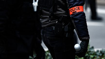 Un policier tient dans la main une grenade de désencerclement lors d'une manifestation contre la réforme des retraites, à Lille, le 23 mars 2023. (SAMEER AL-DOUMY / AFP)