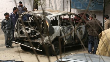 Des enqu&ecirc;teurs autour de la carcasse du v&eacute;hicule touch&eacute; par un attentat &agrave; New Delhi (Inde),&nbsp;le 14 f&eacute;vrier 2012. (PARIVARTAN SHARMA / REUTERS)