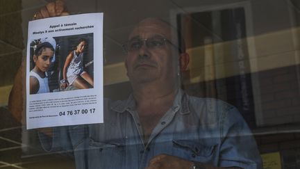 Le propriétaire d'un bar de&nbsp;Pont-de-Beauvoisin (Isère) affiche l'appel à témoin lancé pour retrouver&nbsp;Maëlys, lundi 28 août 2017.&nbsp; (PHILIPPE DESMAZES / AFP)