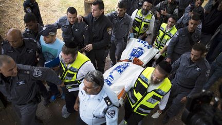 Des policiers isra&eacute;liens transportent le corps du Palestinien ayant attaqu&eacute; un soldat &agrave; Kiryat Gat, le 7 octobre 2015. (AMIR COHEN / REUTERS)