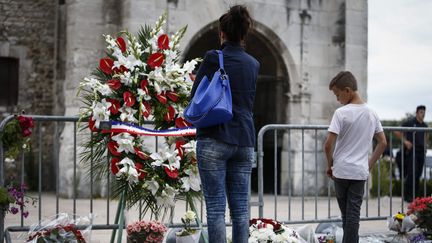 Des personnes se recueillent devant l'église de Saint-Etienne-du-Rouvray (Seine-Maritime), cible d'une attaque terroriste la veille, le 27 juillet 2016. (MAXPPP)