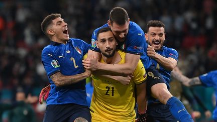 Gianluigi Donnarumma célébré par ses partenaires après la victoire de l'Italie aux tirs au but contre l'Angleterre en finale de l'Euro 2021. (LAURENCE GRIFFITHS / POOL)