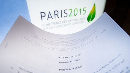 Le logo de la COP21 et un extrait du projet de résultat de la conférence, à Paris, le 10 décembre 2015. Photo d'illustration. (BENOIT DOPPAGNE / BELGA / AFP)