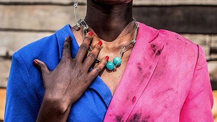 Pamela Tulizo aime aussi détourner les codes de la mode. Comme pour le photographe camerouno-nigérian Samuel Fosso (exposé aussi à la MEP), le vêtement joue un rôle capital dans son travail. Chez elle, l’habit permet l’émancipation et porte le poids du combat des femmes de son pays pour obtenir leur liberté. Le magazine de mode international "Numéro" explique à propos de la photo où une femme tête haute et regard digne fixe le spectateur&nbsp;: "Son corps est divisé en deux parties bien distinctes par une ligne qui la traverse de haut en bas : sur la moitié droite, elle est vêtue d'une veste fuchsia tachée, son visage est couvert de suie et de larmes. Sur la moitié gauche, elle porte un tailleur bleu immaculé, son visage est impeccablement fardé et orné d'une boucle d'oreille argentée. Un corps scindé en deux, illustrant la double identité de la femme africaine. Pauvre et souffrante aux yeux des médias, notamment occidentaux, la première suscite la pitié tandis que la seconde, apprêtée, confiante et maîtresse de sa propre vie, provoque l'admiration." &nbsp; (PAMELA TULIZO)