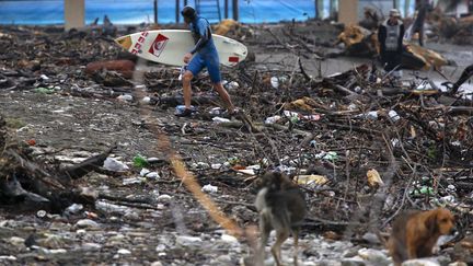 Un surfeur marche sur la plage de Khosta (Russie) jonch&eacute;e de d&eacute;bris, le 25 septembre 2013. (MAXIM SHEMETOV / REUTERS)