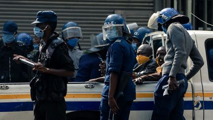 Deux membres du parti d'opposition du Zimbabwe MDC (Mouvement pour un changement démocratique) sont assis à l'arrière d'un camion de police, quelques instants après leur arrestation devant le siège du parti à Harare, le 5 juin 2020. (Jekesai NJIKIZANA / AFP)