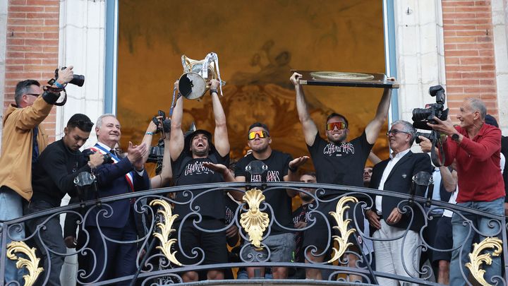 Le maire de Toulouse, Jean-Luc Moudenc, et les joueurs du Stade Toulousain venus célébrer leur victoire sur le balcon de l'hôtel de ville, le 29 juin 2024. (VALENTINE CHAPUIS / AFP)