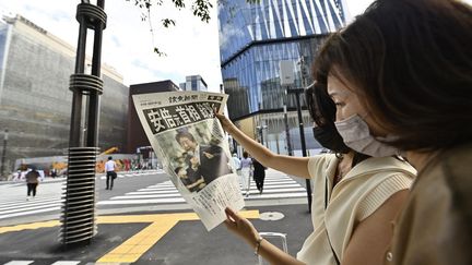 Des Japonais lisent un journal évoquant l'attaque contre Shinzo Abe, alors entre la vie et la mort, à Tokyo, le 8 juillet 2022. Lex-Premier ministre est mort quelques heures plus tard. (DAVID MAREUIL / ANADOLU AGENCY / AFP)