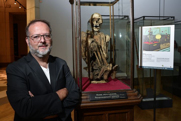 Serge Lemaitre, archéologue et&nbsp;conservateur des collections Amériques du &nbsp;MAH (Musée Art et Histoire) de Bruxelles, pose à côté de la momie présentée&nbsp; comme celle ayant insopiré Hergé pour son persoonage de Rascar Capac, dans l'album "Les 7 boules de cristal". (JOHN THYS / AFP)