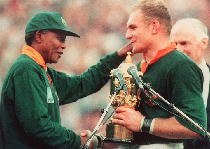 Le président d'Afrique du sud, Nelson Mandela, remet au capitaine de l'équipe de rugby du pays,&nbsp;François Pienaar, la Coupe du monde, le 24 juin 1995, à Johannesbourg. (JEAN-PIERRE MULLER / AFP)