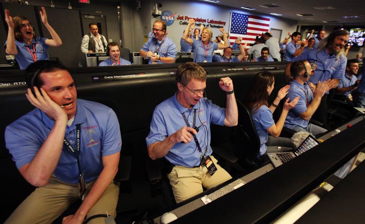 Des ing&eacute;nieurs de la mission Mars Curiosity f&ecirc;tent l'amarssisage r&eacute;ussi de leur robot, le 5 ao&ucirc;t 2012 &agrave; Pasadena (Californie). (BRIAN VAN DER BRUG / AFP)