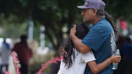 Deux membres d'une même famille se prennent dans les bras à Uvalde, le 24 mai 2022, après une tuerie qui a fait 21 morts dont 19 enfants.&nbsp; (ALLISON DINNER / AFP)