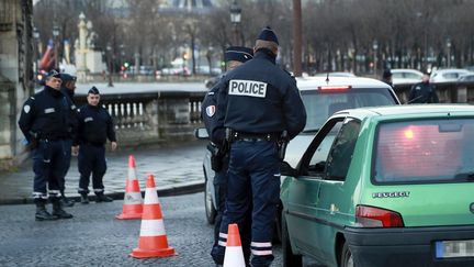 Des agents de police contrôlent un véhicule place de la Concorde à Paris, le 10 janvier 2017, pour vérifier la présence d'une vignette "Crit'Air". (JACQUES DEMARTHON / AFP)