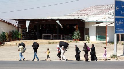 Des personnes portent leurs bagages &agrave; la fronti&egrave;re entre la Syrie et le Liban, o&ugrave; des dizaines de milliers de personnes ont trouv&eacute; refuge le 19 juillet 2012. (AFP )