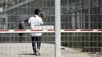  (Un migrant qui porte un enfant dans le camp de Moria sur l'île de Lesbos où 2500 migrants attendent d'être expuslés vers la Turquie  © Petros Giannakouris/AP/SIPA)