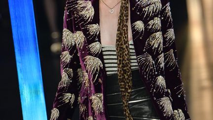 Chez Saint Laurent, le designer Hedi Slimane poursuit sa plongée en mode rétro. En juin, pour l'homme, il avait présenté une collection hippie chic très inspiration 70, cette fois-ci pour la femme, la silhouette est nettement plus urbaine. Dynamique et très courte vêtue, la très jeune femme Saint Laurent aime incontestablement les petites robes fleuries très très échancrées et coupées mi cuisse. Elle adopte les jupes droites très sixties parfois en jean ou en peau ainsi que les shorts à porter avec un blouson en cuir. Très peu de pantalons mais encore du noir et des brillances pour le soir. Les précédentes collections d'Hedi Slimane pour Saint Laurent étaient très rock et cette influence est toujours présente, avec perfectos et vestes brillantes.
 (MIGUEL MEDINA / AFP)