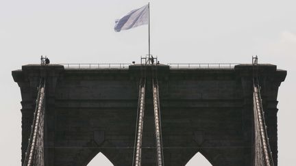 Des policiers new-yorkais interviennent sur le pont de Brooklyn (Etats-Unis) pour enlever un drapeau blanc, hiss&eacute; &agrave; la place du drapeau am&eacute;ricain, mardi 22 juillet 2014.&nbsp; (RICHARD DREW / AP / SIPA)