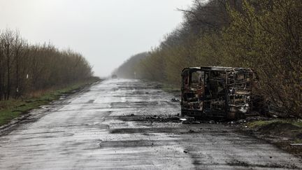 Une camionnette incendiée sur une route de Popasna, dans le Donbass, le 14 avril 2022. (RONALDO SCHEMIDT / AFP)