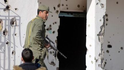 Un militaire tunisien devant une maison criblée de balles lors de l'opération djihadiste à Ben Guerdane le 7 mars 2016. Une preuve de la violence des combats. (AFP - Fathi Nasri)