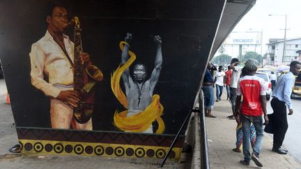 A quelques mètres, les passants marchent devant le portrait de l'immense chanteur, saxophoniste, inventeur de l’afrobeat et figure politique, Fela Kuti. (PIUS UTOMI EKPEI / AFP)