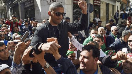 Des manifestants portent le journaliste algérien Khaled Drareni après&nbsp;avoir été détenu par des forces de sécurité, le 6 mars 2020 à Alger (Algérie).&nbsp; (RYAD KRAMDI / AFP)