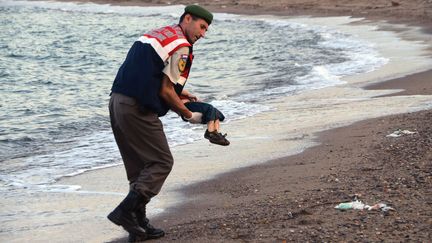 Un officier turc &eacute;vacue le corps d'un jeune migrant mort, le 2 septembre 2015 &agrave; Bodrum (Turquie). (SIPA / AP)