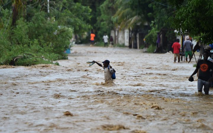 Des habitants d'Haïti tentent de traverser la rivière La Rouyonne dans la commune de Leogane, au sud de Port-au-Prince, le 5 octobre 2016. (HECTOR RETAMAL / AFP)