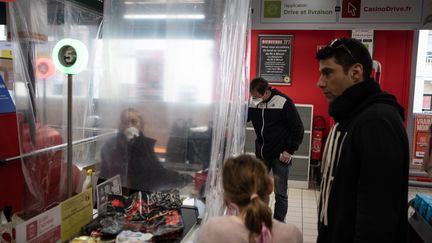 Les employés des commerces alimentaires sont sur le pont pendant la crise sanitaire. Cette salariée est protégée par un rideau en plastique à Nantes (Loire-Atlantique), le 20 mars 2020. (J?R?MIE LUSSEAU / HANS LUCAS / AFP)