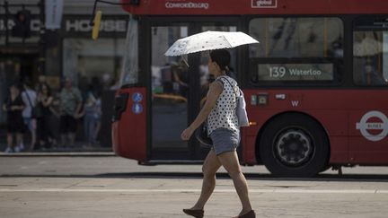 Une passante s'abrite du soleil à Londres (Royaume-Uni), le 18 juillet 2022. (RASID NECATI ASLIM / ANADOLU AGENCY / AFP)