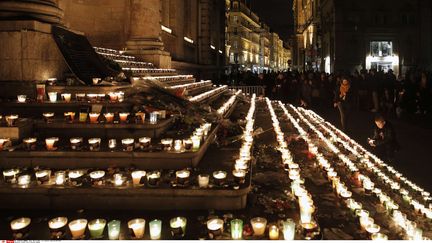 Les passants&nbsp;se sont réunis en silence autour d'autels spontanés&nbsp;installés un peu partout dans le vieux Lyon, comme ici sur les marches de l'hôtel de ville. (LAURENT CIPRIANI / AP / SIPA)