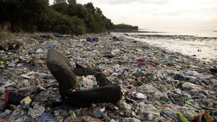 Photographie prise le 19 mai 2018 montrant une chaise entourée de déchets plastiques sur une plage de la zone d'habitat de Freedom island, près de Manille. (NOEL CELIS / AFP)