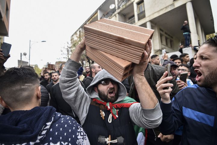 Un manifestant brandit des briques, à Tizi Ouzou le 8 décembre, pour contester la tenue de la présidentielle.&nbsp; (RYAD KRAMDI / AFP)