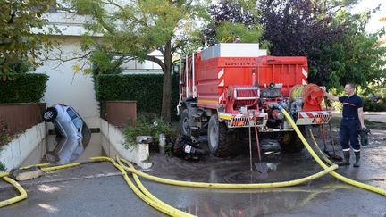 Les pompiers drainent l'entr&eacute;e d'un garage pour r&eacute;cup&eacute;rer un v&eacute;hicule, &agrave; Mandelieu-la-Napoule. (BORIS HORVAT / AFP)